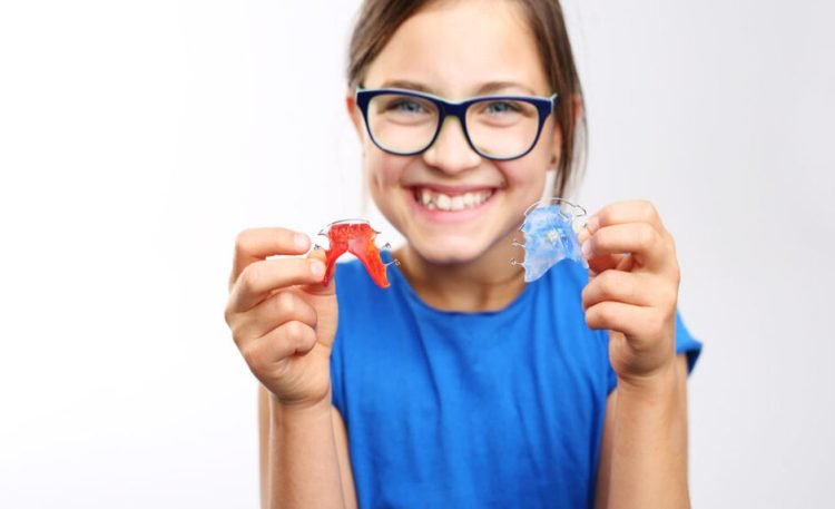 Pretty girl with colored orthodontic appliance .